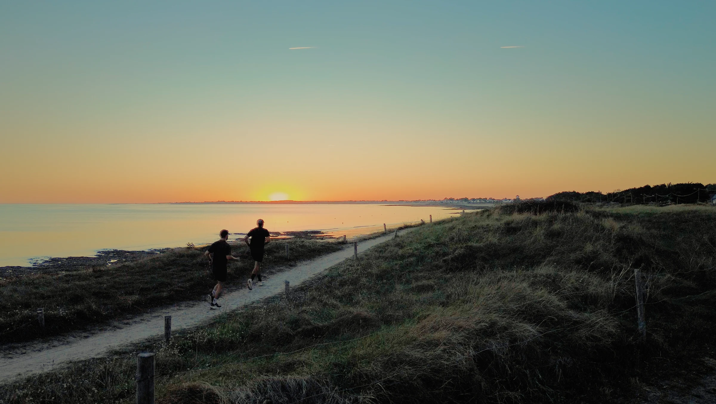 Deux coureurs sur le sentier des dunes de Damgan au coucher du soleil