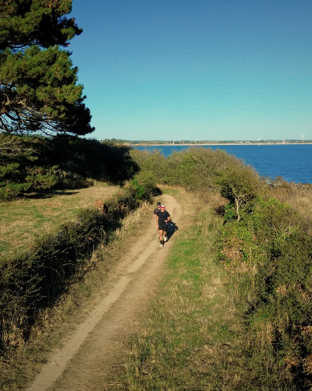 Deux coureurs sur le sentier côtier, la baie en contrebas